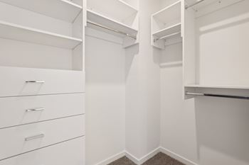 A white walk-in closet with shelves and drawers.